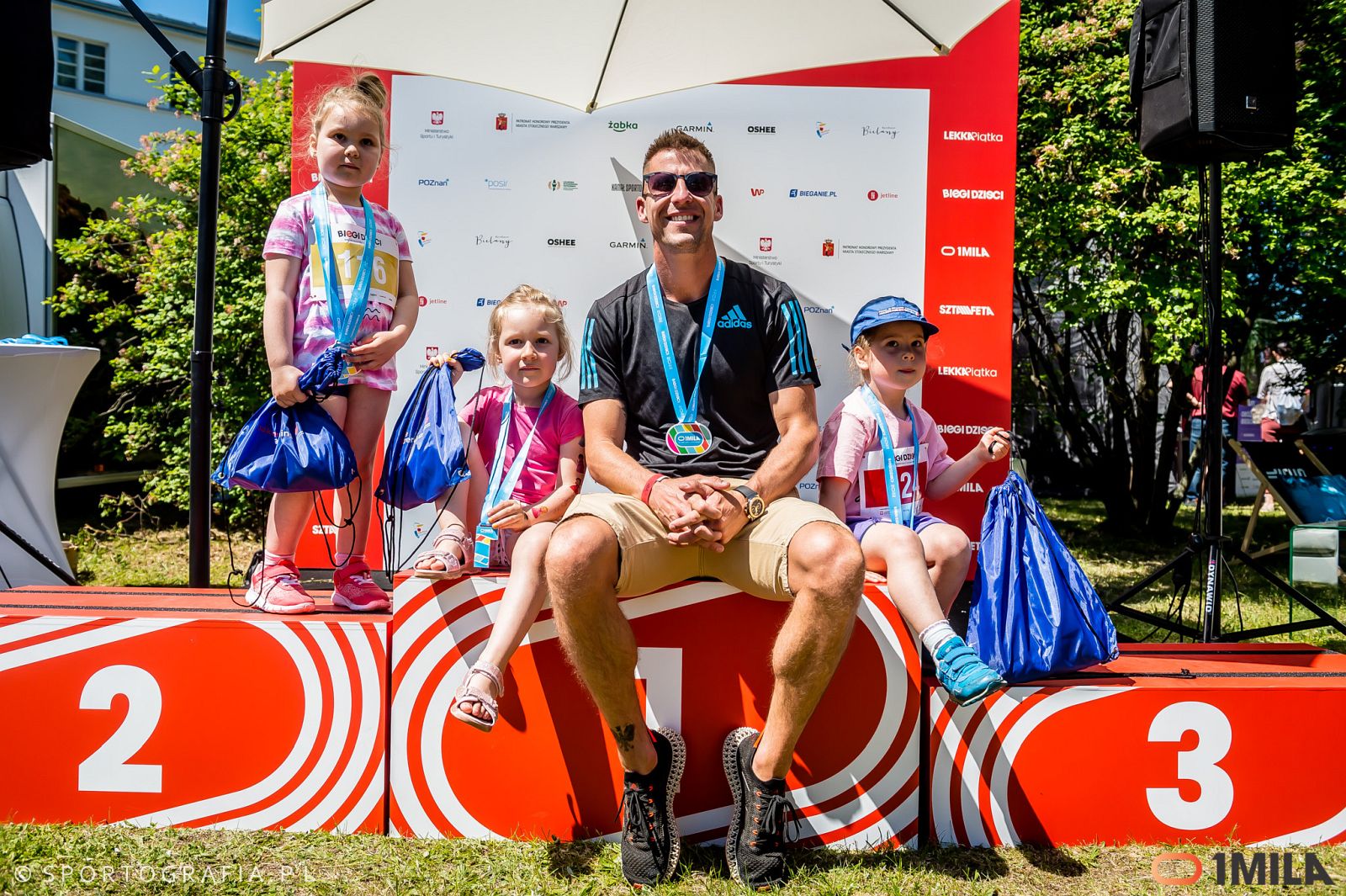 Marcin Lewandowski razem z dziećmi na podium biegu 1 Mila